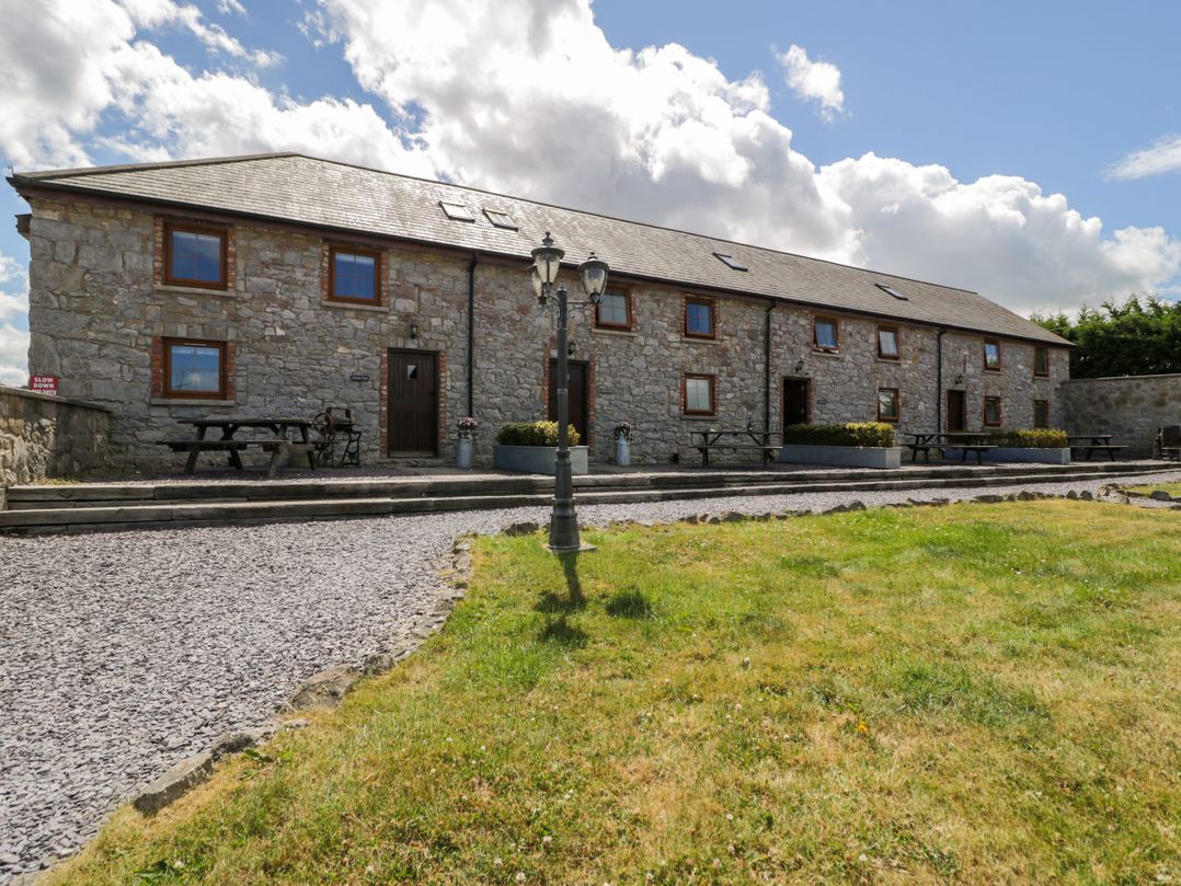 A stone building with picnic tables at Bwthyn Y Wennol in Dolwen near Abergele
