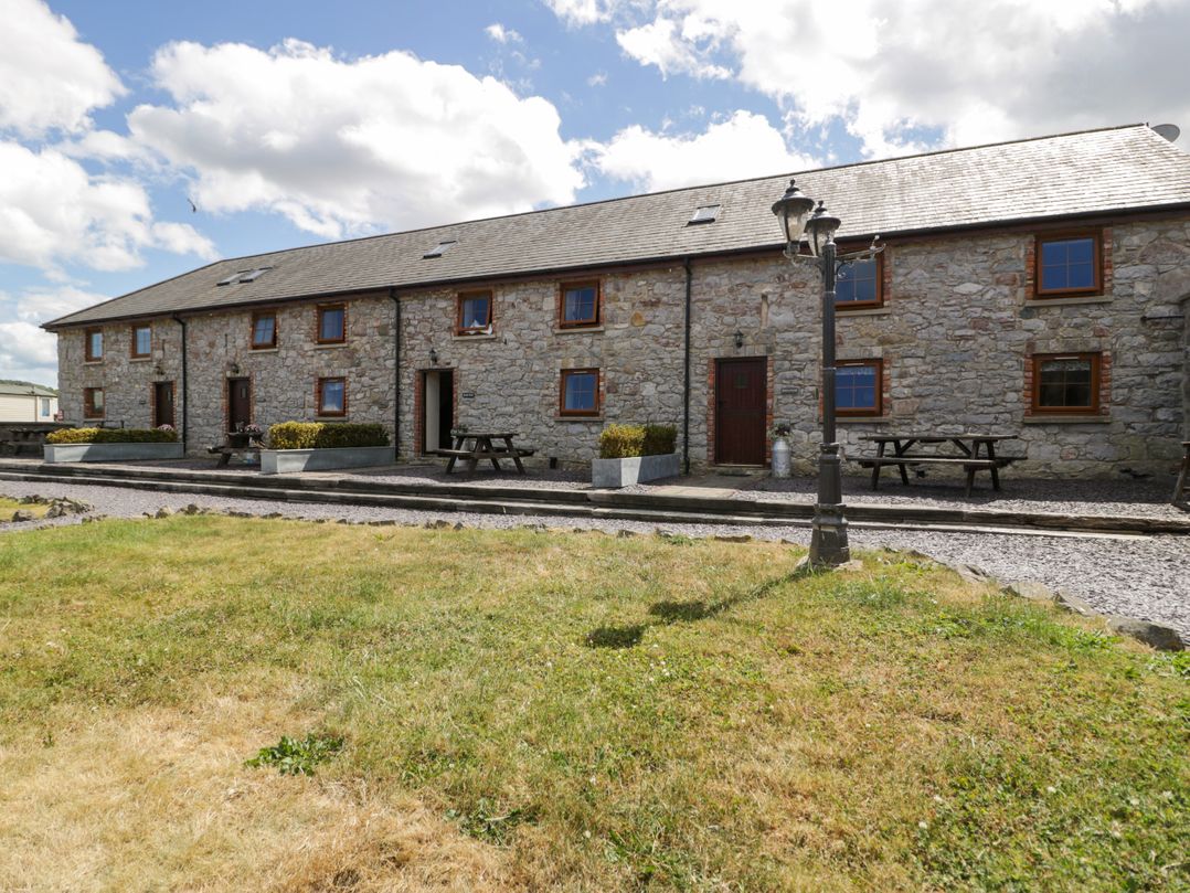 An outdoor area with a stone building and seating at Bwthyn Y Wennol Dolwen near Abergele