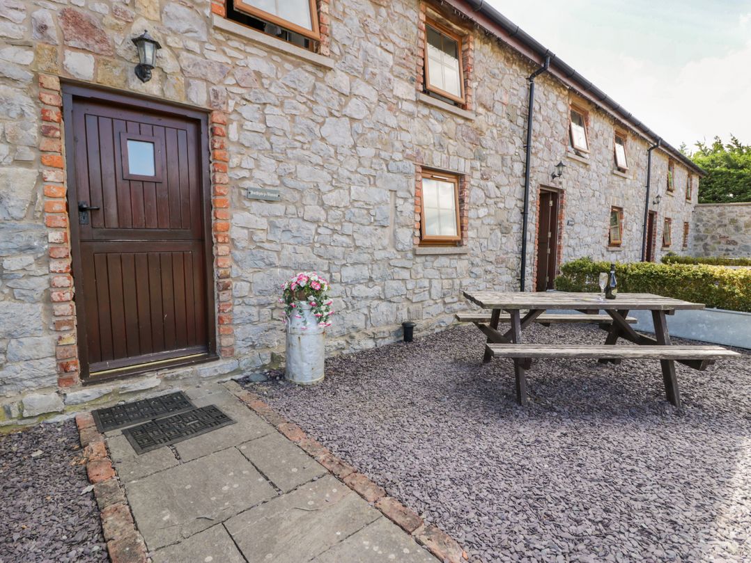 An outdoor area with a stone wall and picnic table at Bwthyn Y Wennol near Abergele