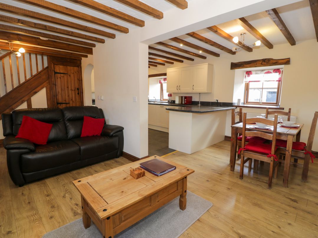 A living room with a sofa and dining area at Bwthyn Y Wennol in Dolwen near Abergele