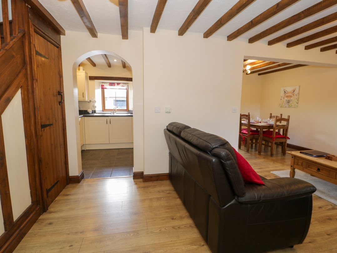 A living room with a sofa and dining area at Bwthyn Y Wennol Dolwen near Abergele