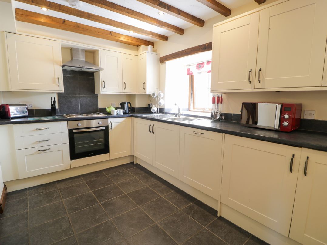 A kitchen with cabinets and appliances at Bwthyn Y Wennol in Dolwen near Abergele