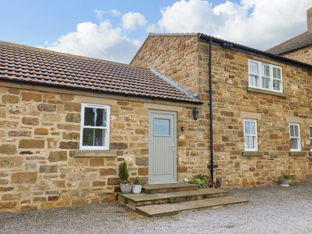 An outdoor view of a cottage with a door and windows at Fell Briggs Cottage, Marske-By-The-Sea
