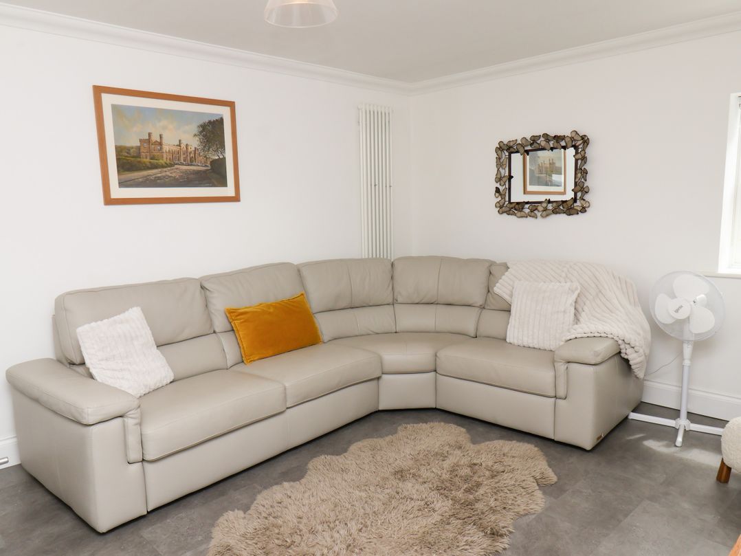 A living room with a sectional sofa and artwork at Fell Briggs Cottage in Marske-By-The-Sea