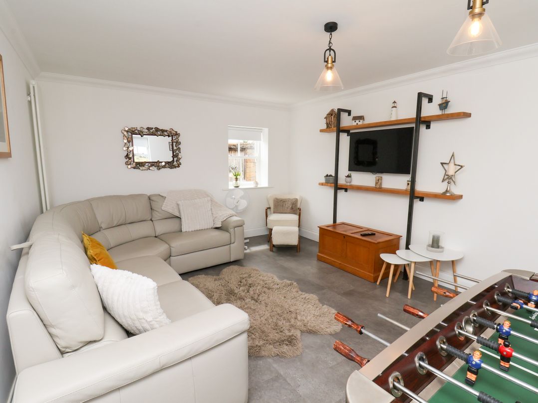 A living room with a sofa, foosball table, and television at Fell Briggs Cottage in Marske-By-The-Sea