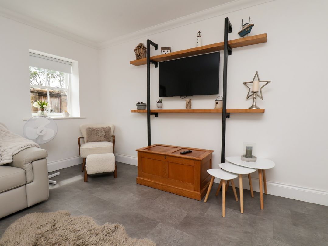 A living room with a television and wooden furniture at Fell Briggs Cottage in Marske-By-The-Sea