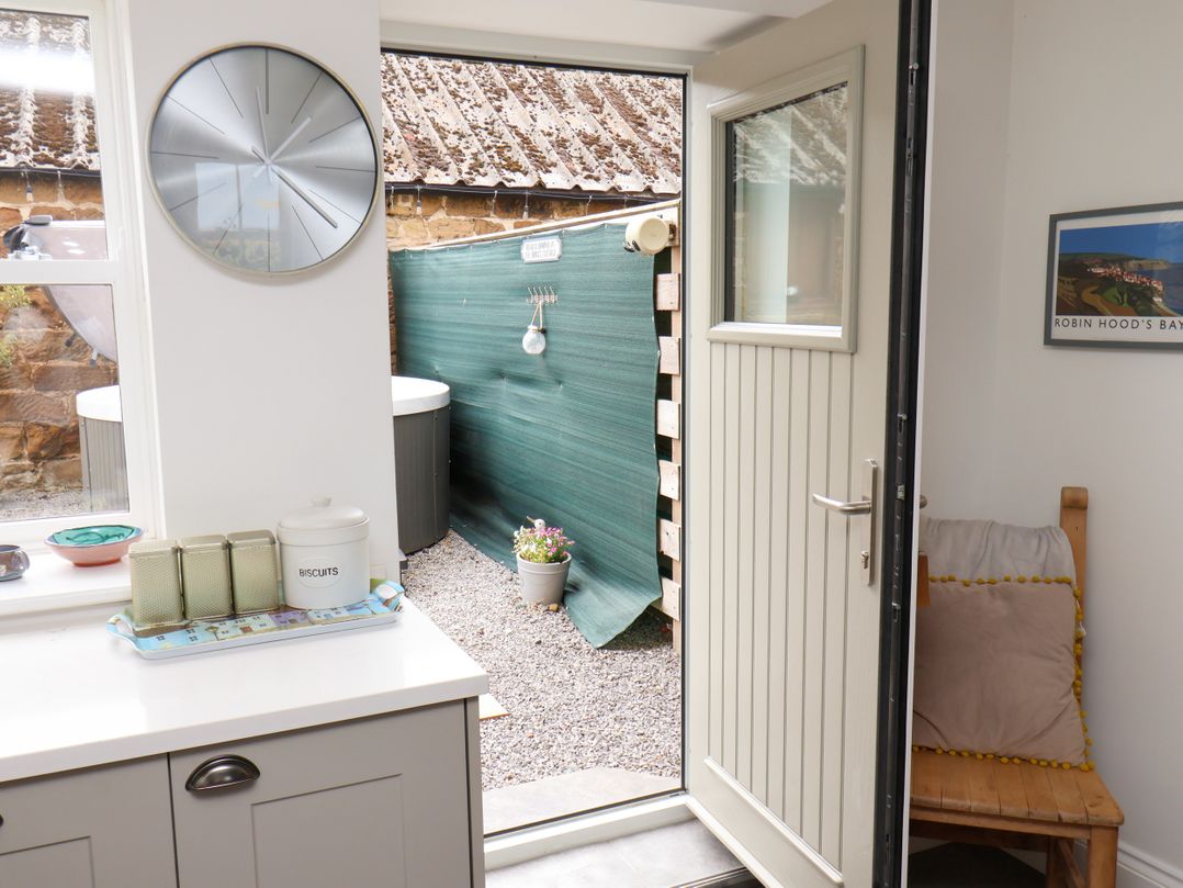 A kitchen with an open door leading to a garden area at Fell Briggs Cottage in Marske-By-The-Sea