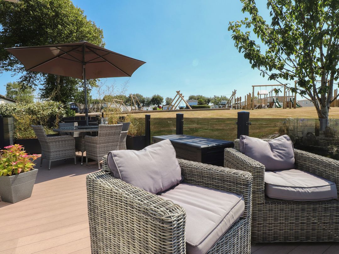 An outdoor patio with seating and a playground in the background at 97 Crugan Llanbedrog