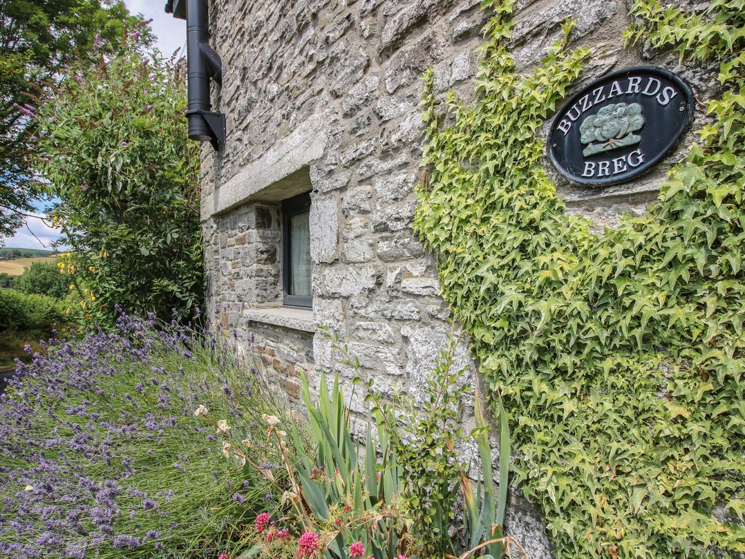 A stone wall with a house sign and plants at Buzzards Breg in Builth Wells