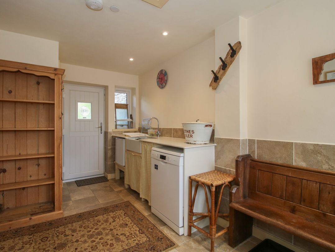 A kitchen with a sink, dishwasher, storage cabinet and a wooden bench at Buzzards Breg in Builth Wells