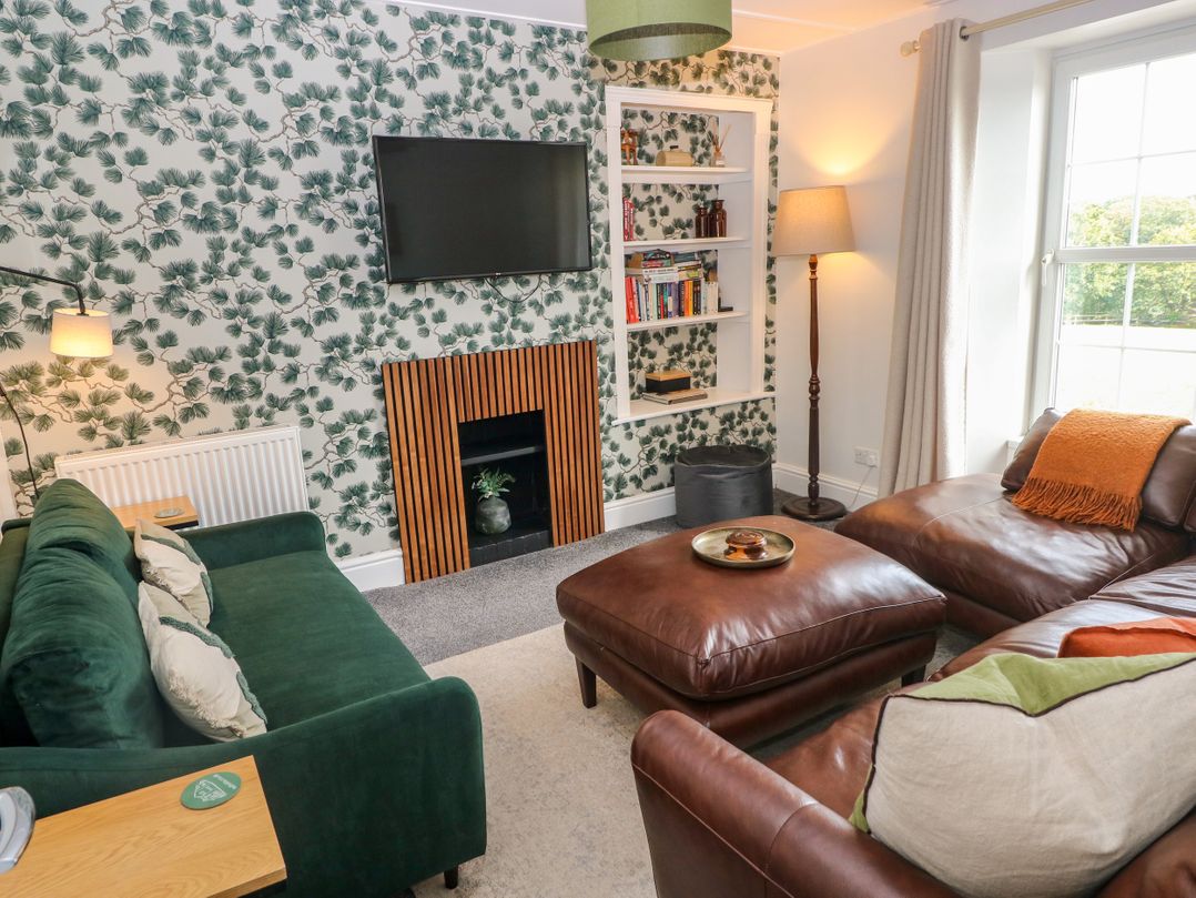 A living room with a sofa, television, and bookshelf at Teifi Villa in St Dogmaels