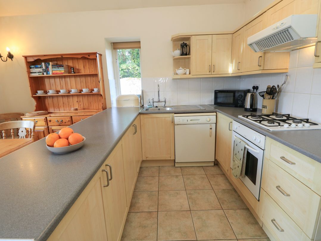 A kitchen with wooden cabinets and modern appliances at Byre Cottage 2 in Sullington near Storrington