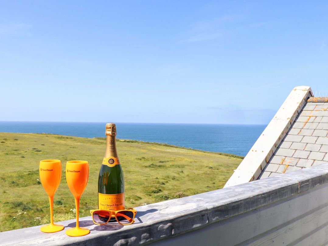 A champagne bottle and glasses on a balcony with a sea view at Penthouse 23 in Newquay