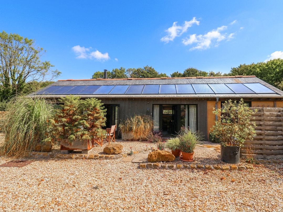 An outdoor view of a building with solar panels and plants at The Dairy in Bridport
