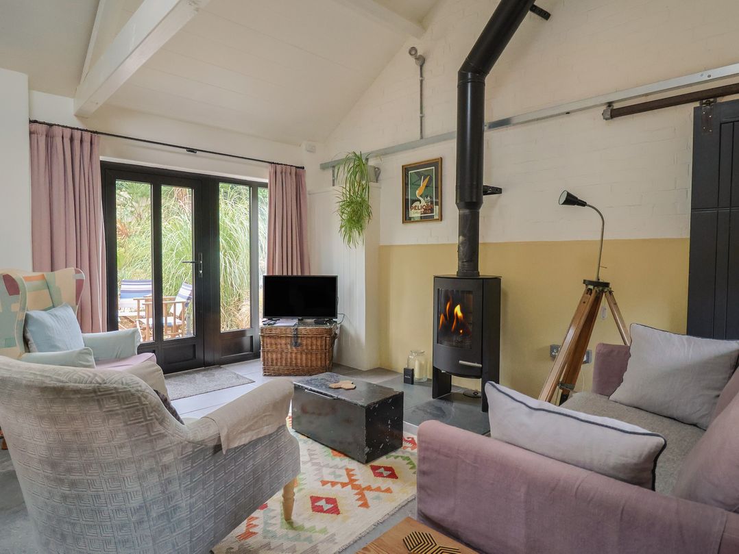A living room with a wood stove and television at The Dairy in Bridport