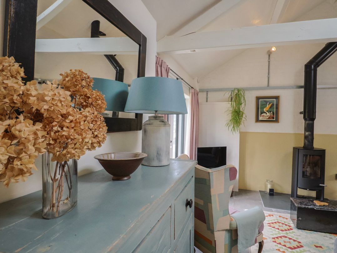 A living room with a mirror, lamp, sofa and stove at The Dairy in Bridport