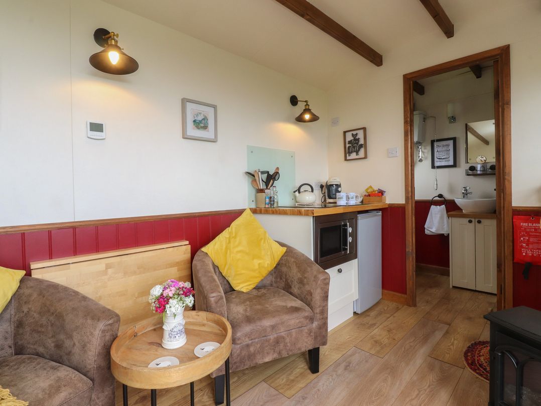 A snug area with seating and kitchenette at The Herdsman Luxury Shepherds Hut in Barnoldswick