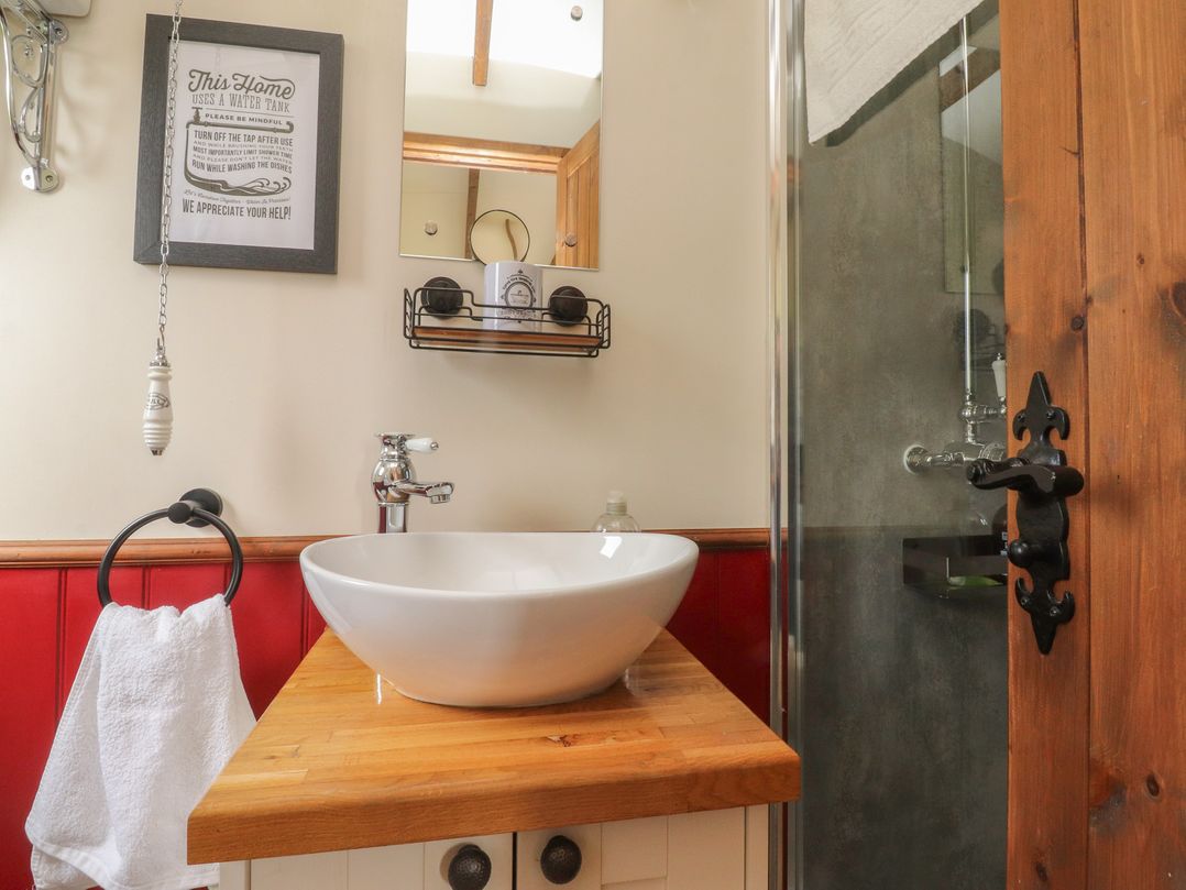 A bathroom with a wash basin and shower at The Herdsman Luxury Shepherds Hut Barnoldswick
