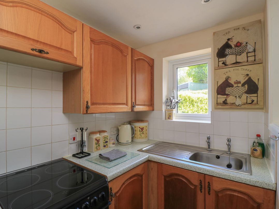 A kitchen with cabinets, stove, sink, and window at Ryecross Farm Cottage in Shaftesbury