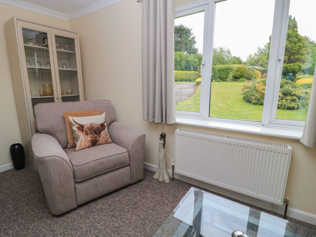 A living room with an armchair and a glass table at Ryecross Farm Cottage in Shaftesbury