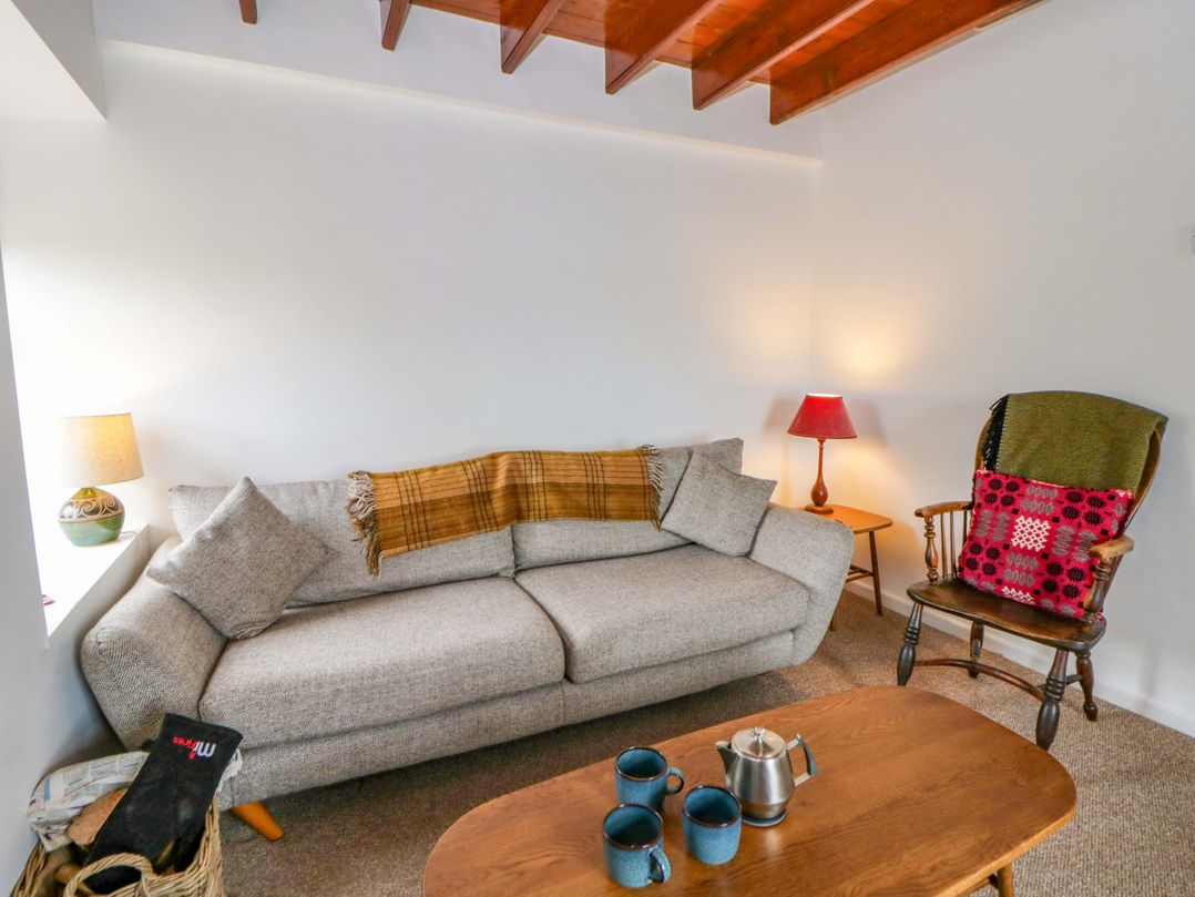 A living room with a sofa, table, and lamp at Ceunant near Newport