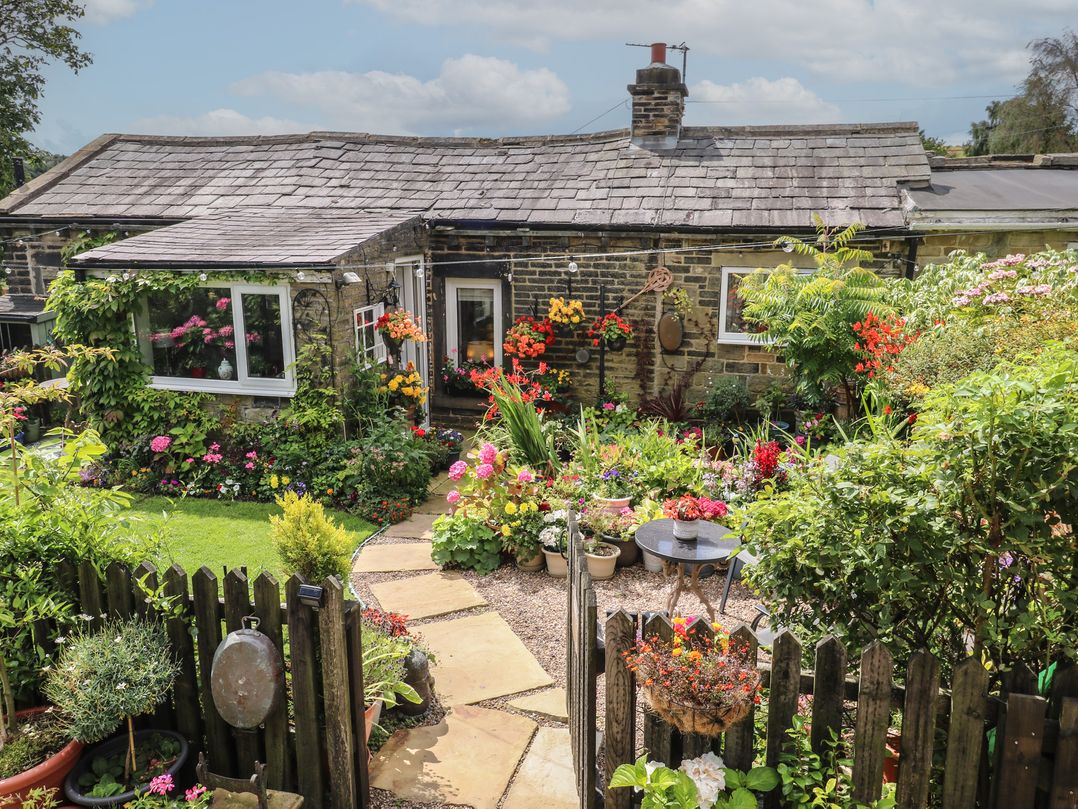 A garden with flowers and a stone path at Prospect Cottage in Ripponden