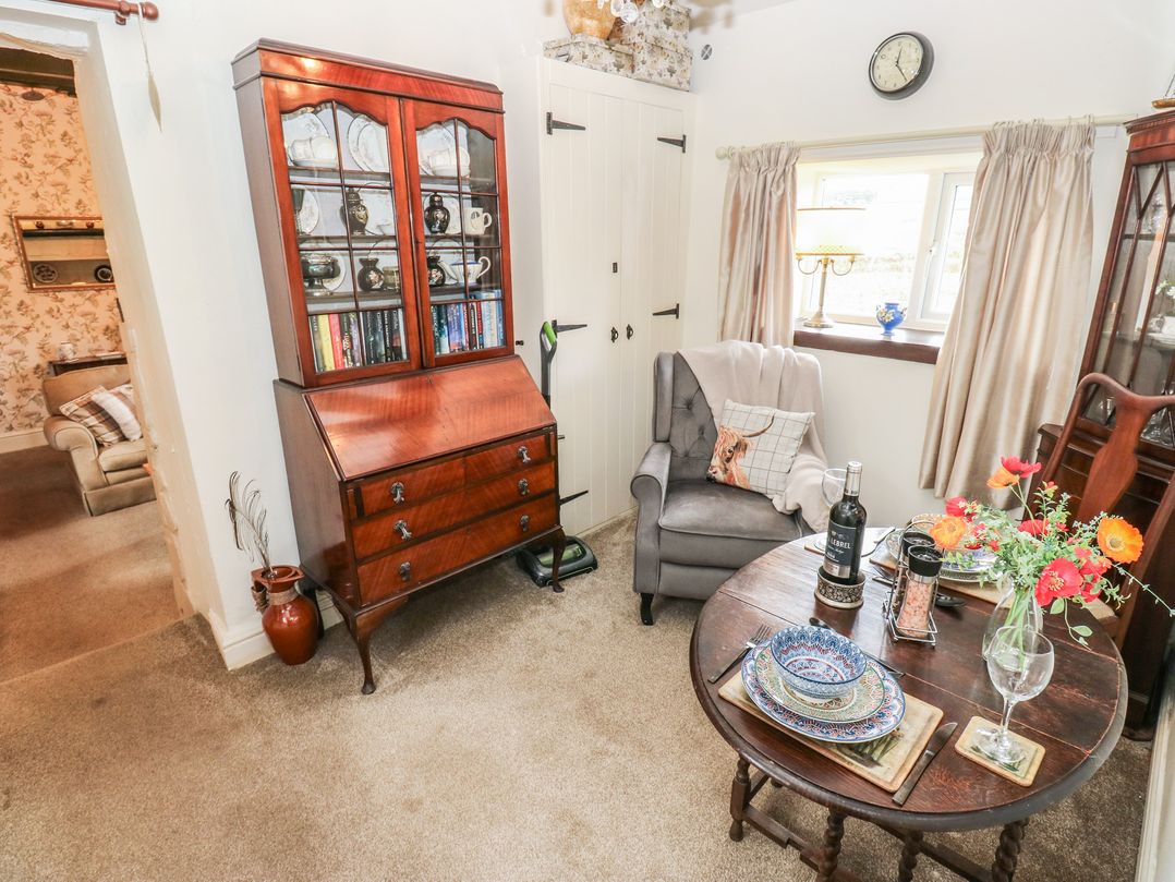 A living room with a bookshelf and dining table at Prospect Cottage in Ripponden