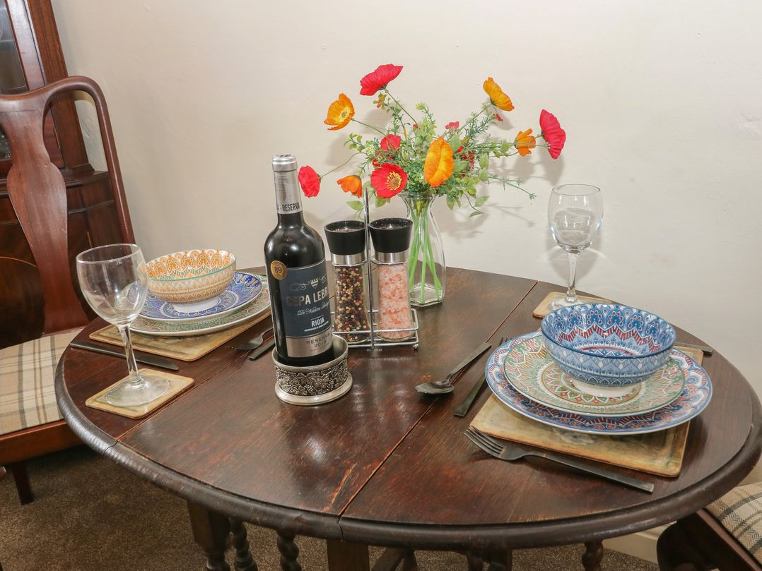 A dining table set with wine, glasses, plates and flowers at Prospect Cottage in Ripponden