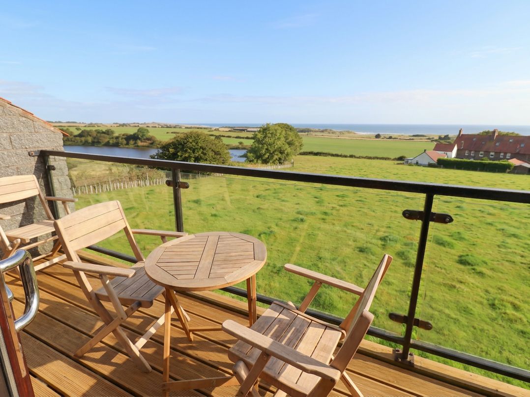 A balcony with a table and chairs overlooking the ocean at Links View in Embleton