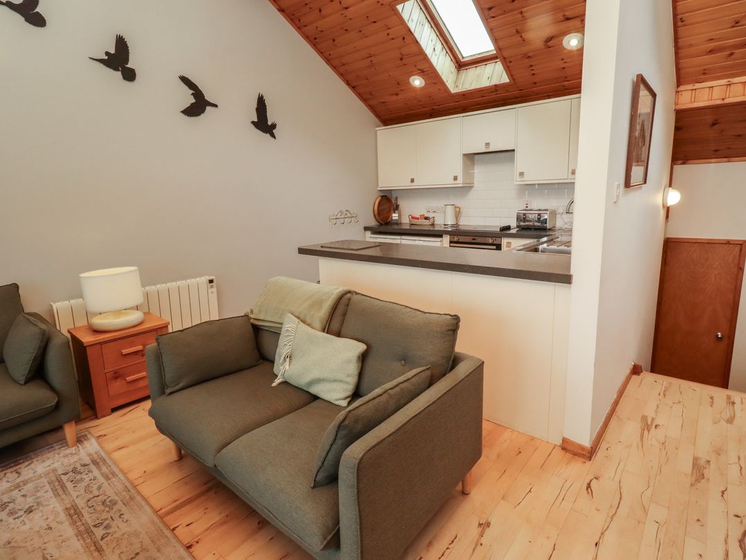 A living room with a sofa and kitchen area at Links View in Embleton