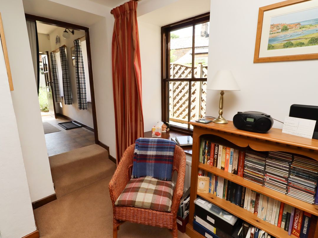 A hallway with a chair and bookshelf at Lavender Cottage (Bailiffgate) Alnwick