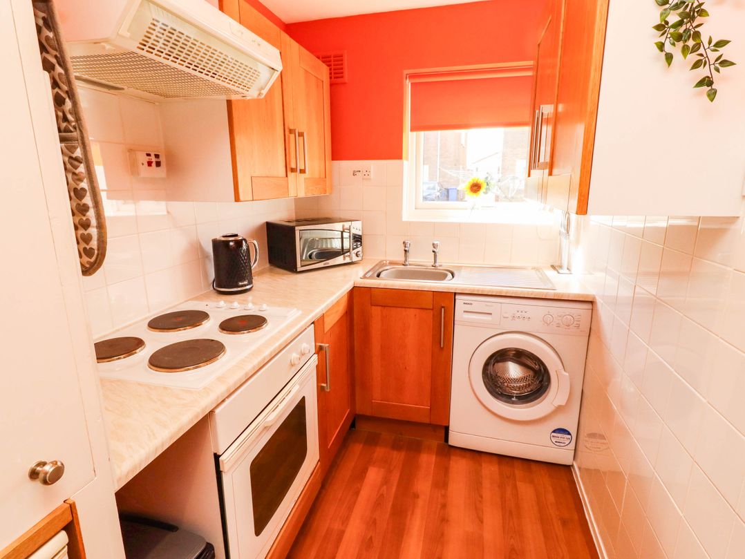 A kitchen with an oven, stove, microwave, kettle, sink, and washing machine at Flora Cottage Beadnell