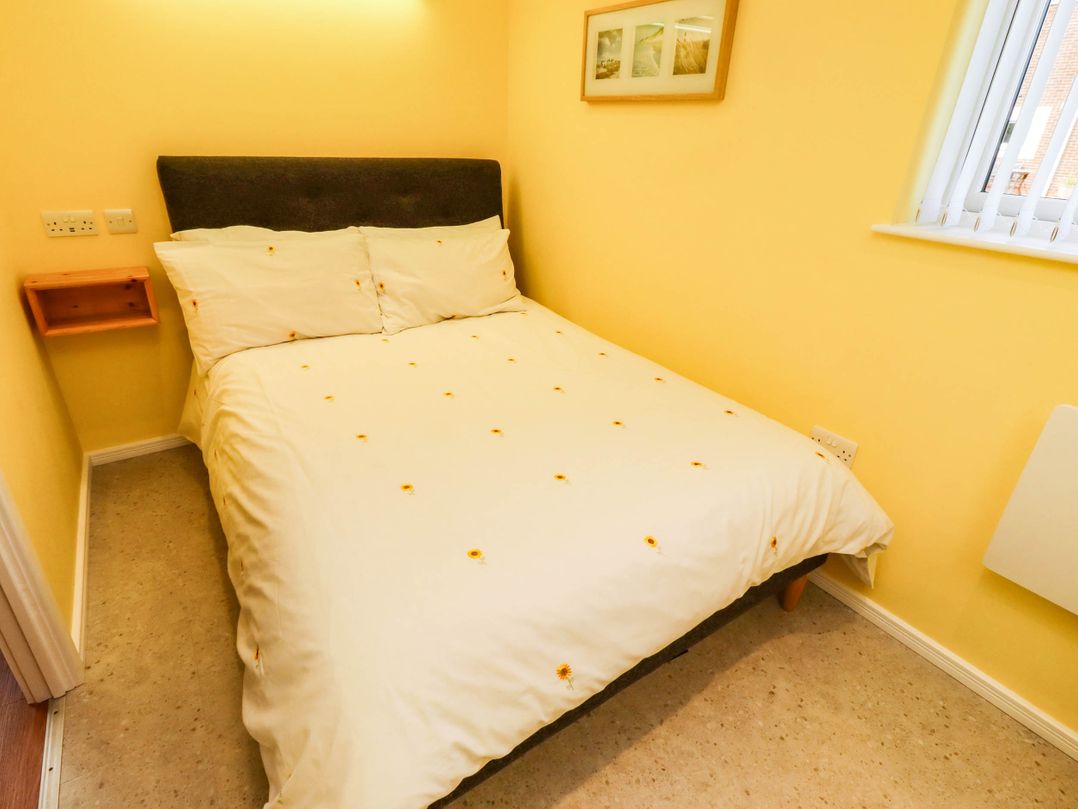 A bedroom with a bed and bedside shelf at Flora Cottage in Beadnell