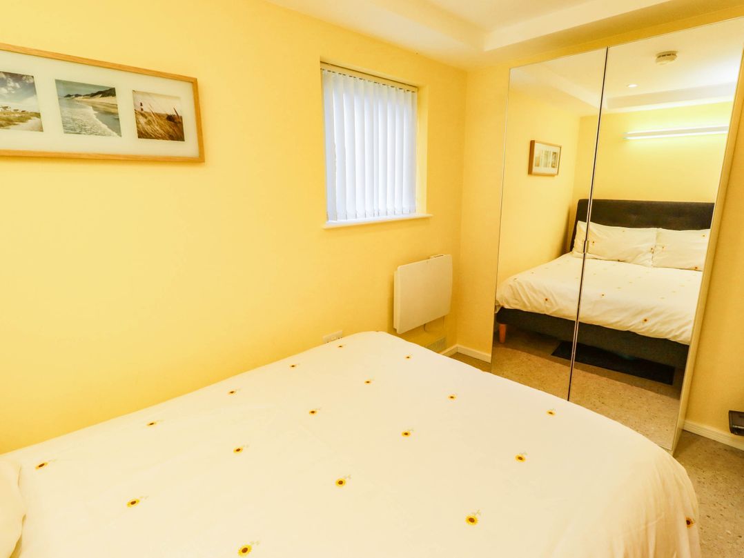 A bedroom with a bed and a mirror at Flora Cottage Beadnell
