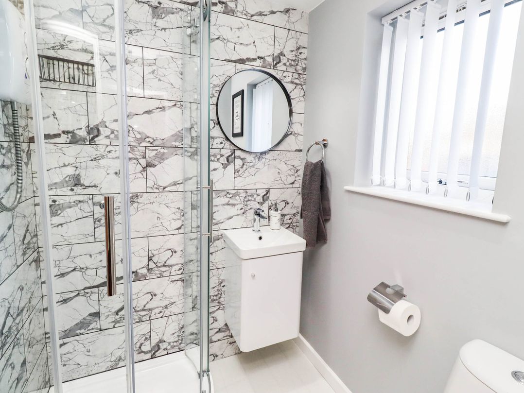 A bathroom with a shower, sink, and toilet at Flora Cottage in Beadnell