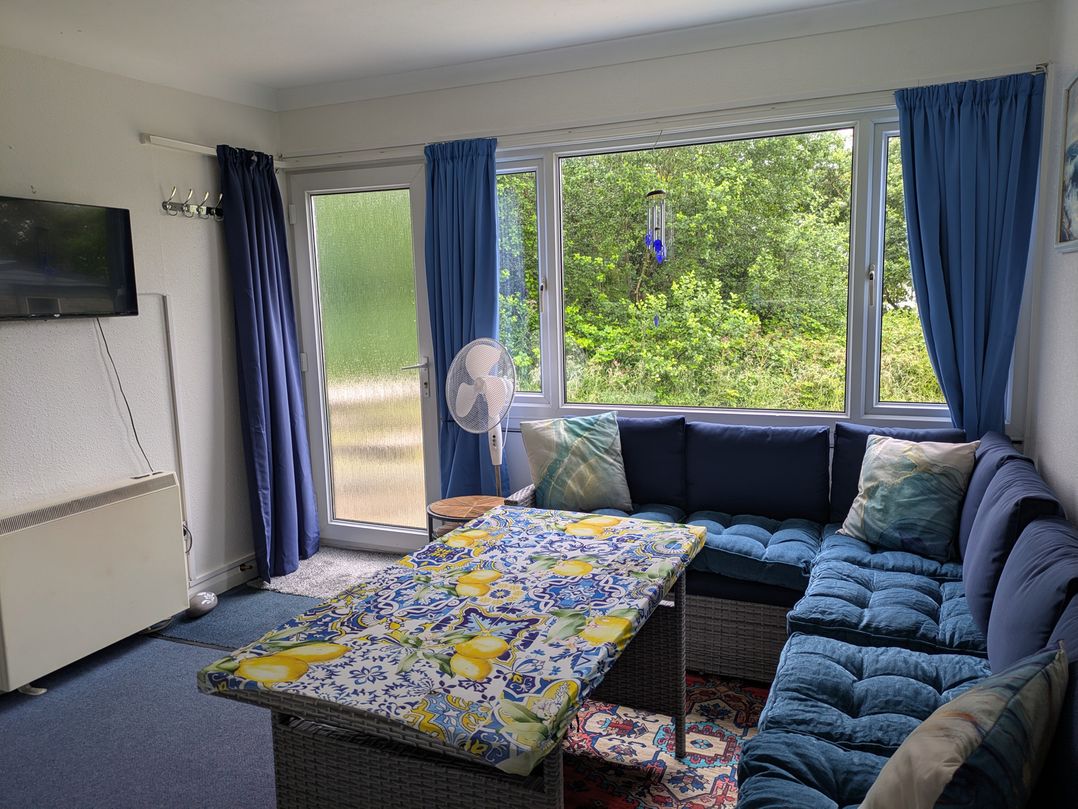 A snug with a sofa and table in front of a window at 21 The Glade in Kilkhampton