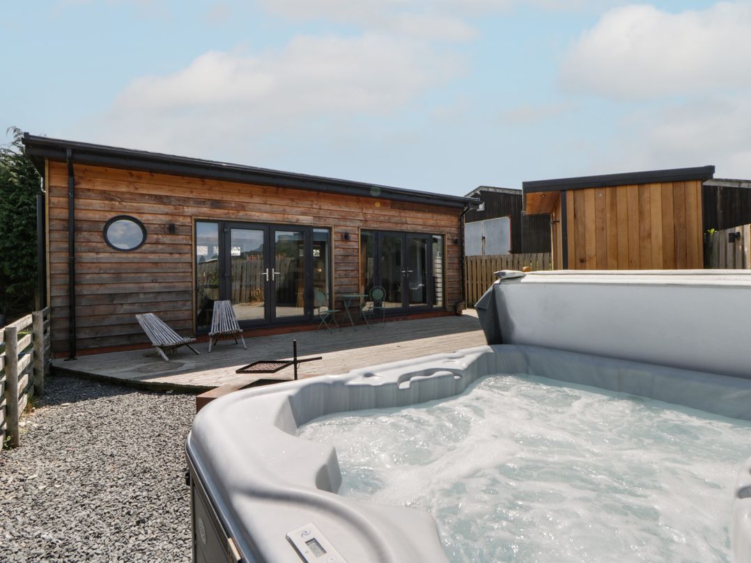 An outdoor area with a hot tub and wooden building at Tin Shed in Nantmel near Rhayader