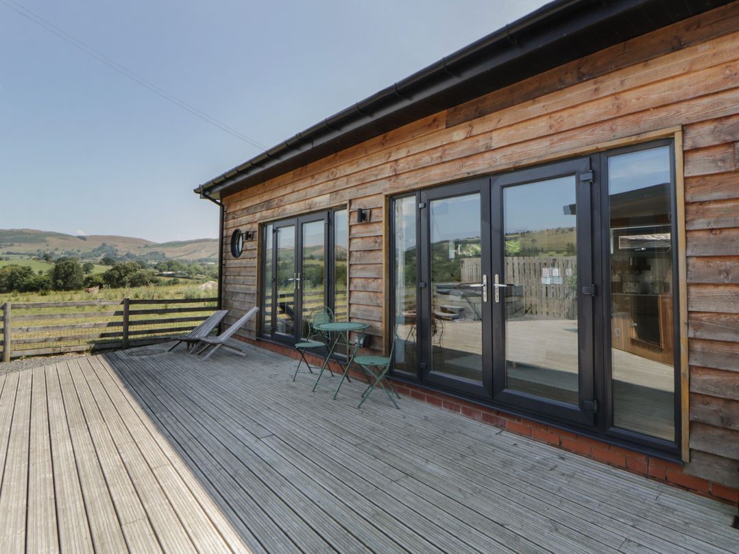 An outdoor deck area with seating and sliding doors at Tin Shed Nantmel near Rhayader