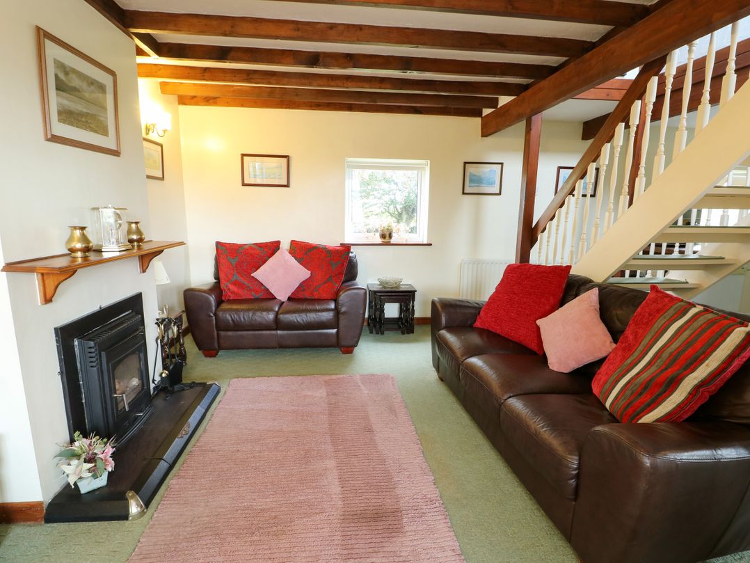 A living room with a fireplace and two sofas at The Cottage at Ty Newydd in Brynsiencyn