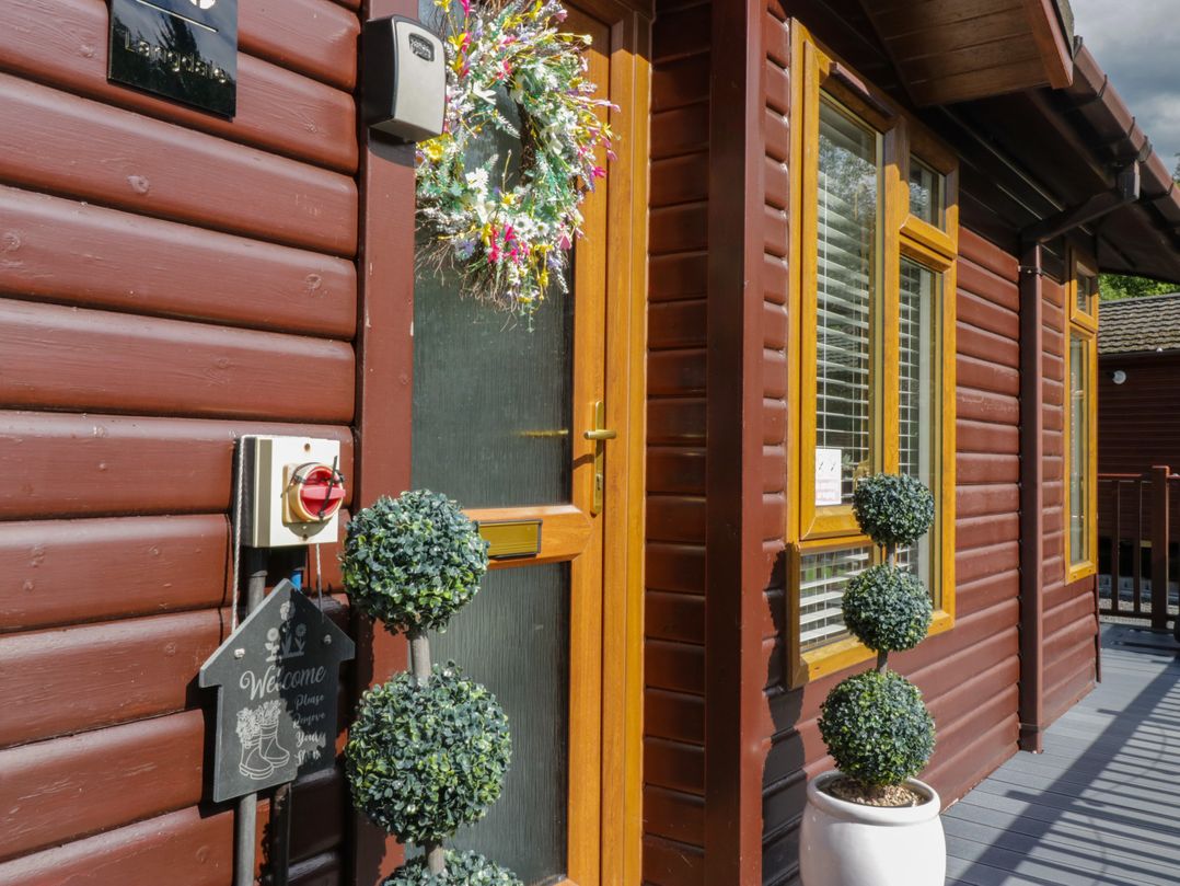 An entrance with a welcome sign and topiary plants at Ruskin Lodge, Langdale 16, White Cross Bay near Windermere