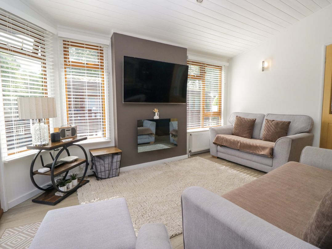A living room with a television mounted on the wall at Ruskin Lodge, Langdale 16, White Cross Bay near Windermere