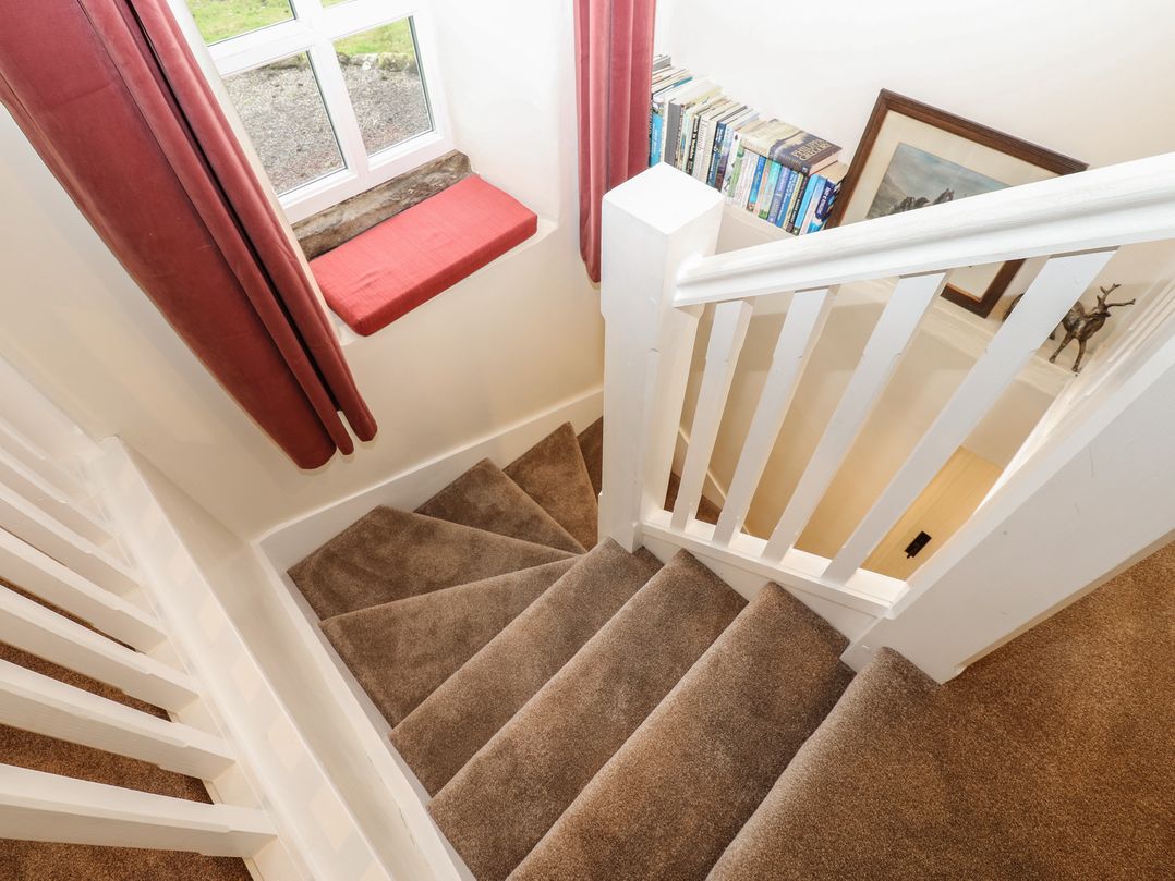 A staircase with a window and books at The LA'AL Cragg in Kirkby Stephen