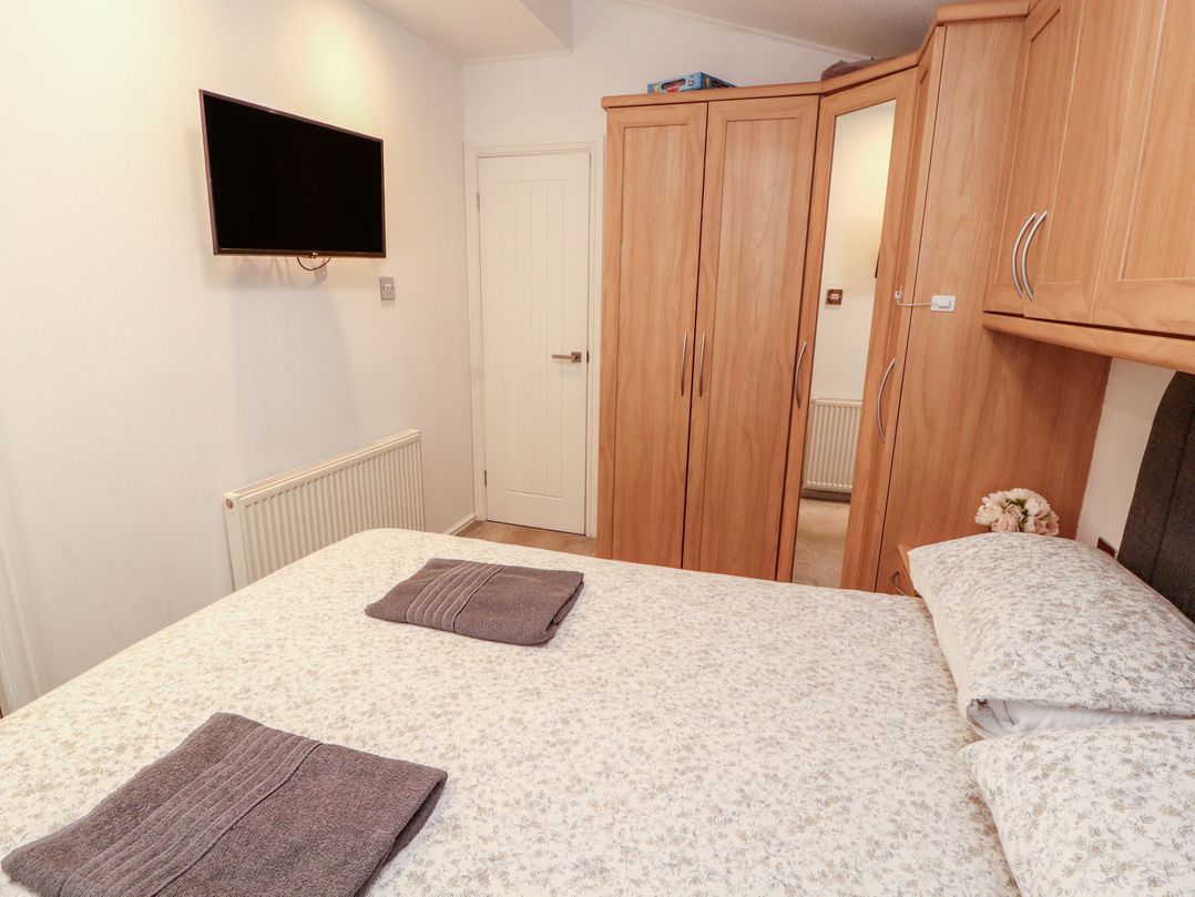 A bedroom with a bed and wardrobe at Willows Lodge near Windermere