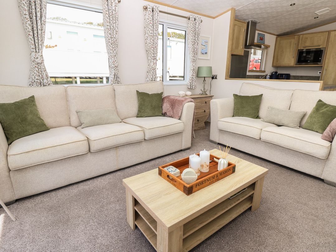 A living room with sofas, a coffee table, and a lamp at 31 Crosswinds in Bembridge