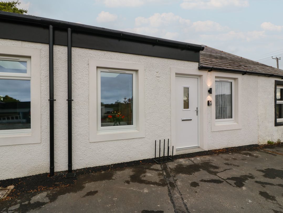 An exterior view of a house with windows and a door at Rosalin Cottage in Dreghorn near Irvine
