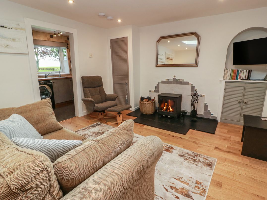 A living room with a fireplace and sofa at Rosalin Cottage in Dreghorn near Irvine