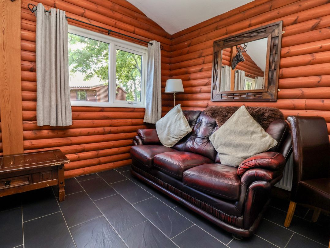 A living room with a leather sofa and window at The Red in Llanerch Park near St Asaph