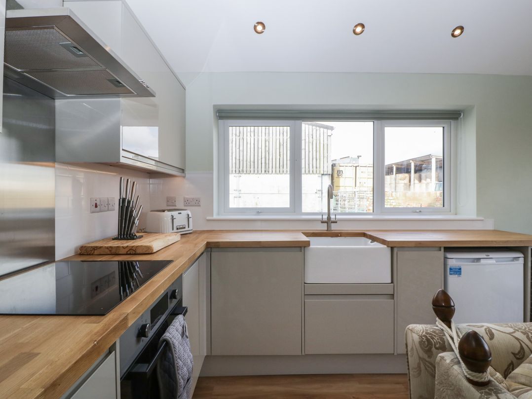 A kitchen with wooden countertops a white sink a knife set a toaster and a small refrigerator at Doubletree Cottage in Swainsford near Mere