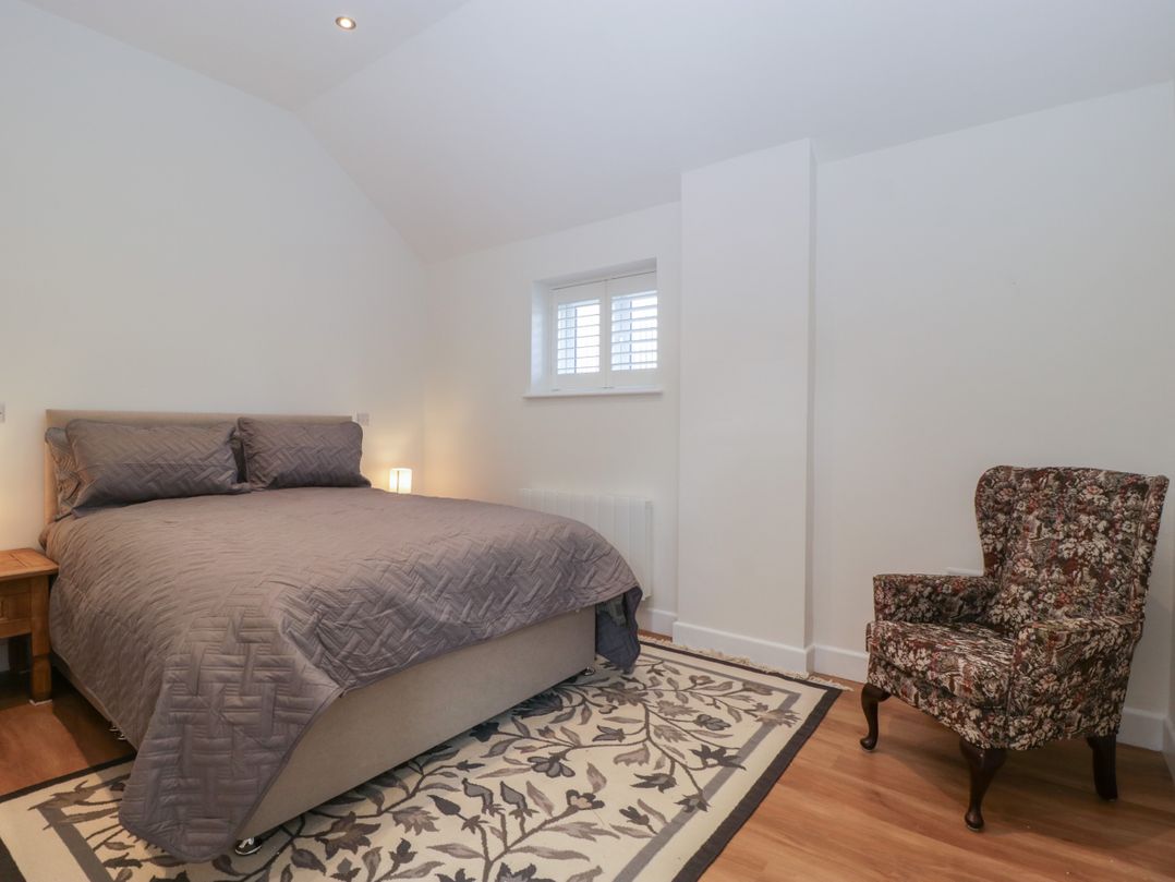 A bedroom with a double bed bedside table lamp patterned armchair and a patterned rug at Doubletree Cottage Swainsford near Mere