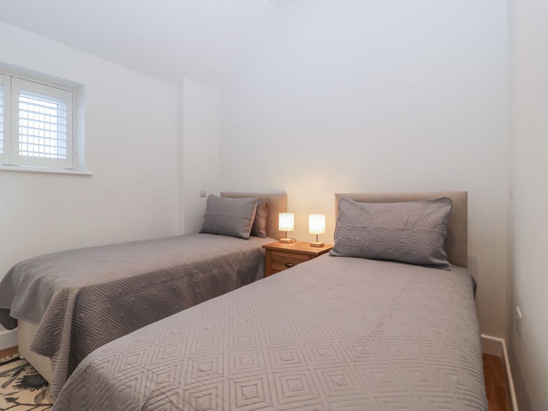 A bedroom with two single beds and a wooden nightstand with lamps at Doubletree Cottage in Swainsford near Mere